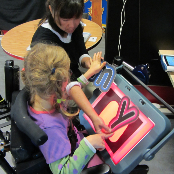 Image of a teacher holding the letters n and y in separate hands while a student holds her hand over the n