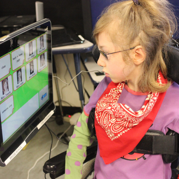 Image of a child looking sideways at an AAC device